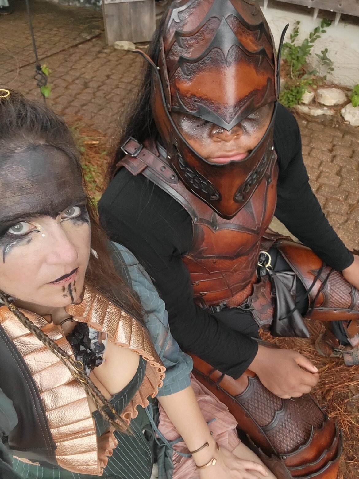 Overslady (left) posing comically with Justin Cale II (right) outdoors in renaissance faire garb. Justin wears a brown leather prince armory fantasy set and overslady wears a pirate outfit with black face makeup.