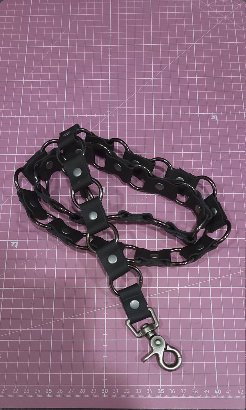 A black leather ring belt with a silver rings lobster claw hook.