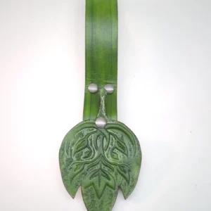 A close up of the front of a green skirt hike against a white background. Displays the skirt hike's green strap and embossed fantasy leaf design on the emblem.